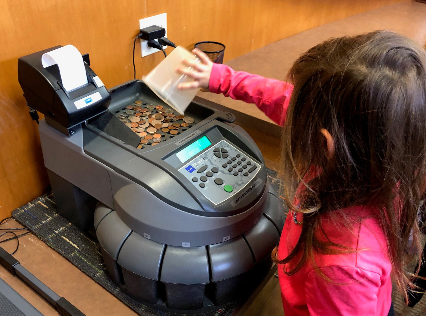 Preschool student learns how to load coin counting machine