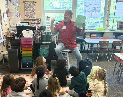 Photo of IUCU employee reading a book to a classroom of children