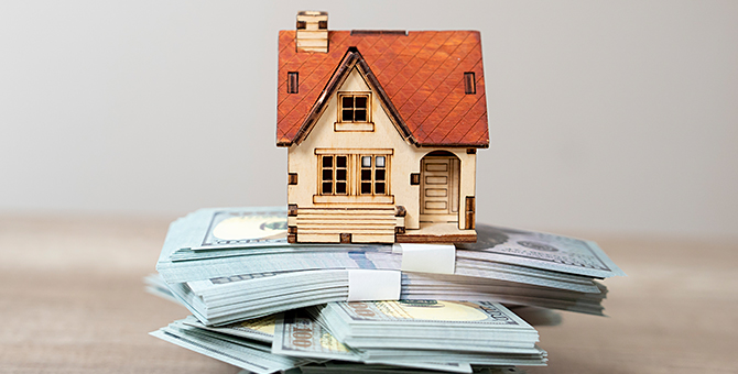 Photo of a model home on a stack of money