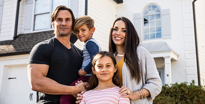 Photo of a young family outside of their home.