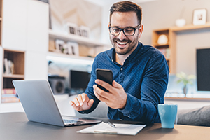 Photo of man using cellphone and computer